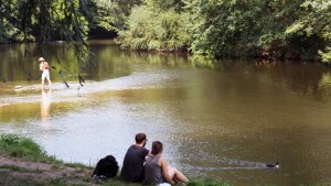 Zwei Menschen sitzen an der Saale in Jena